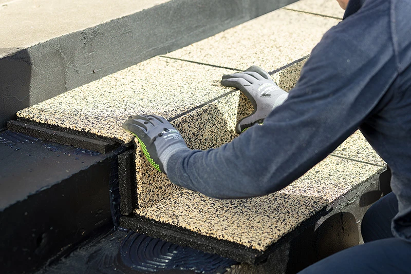 Man glues down steps. Yellow stair covering is glued to the tread and to the nosing step.