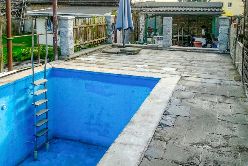 This swimming pool in the garden is in need of complete renovation. Not only the concrete pool itself, but also the terrace and coping are completely weathered and need to be renewed.