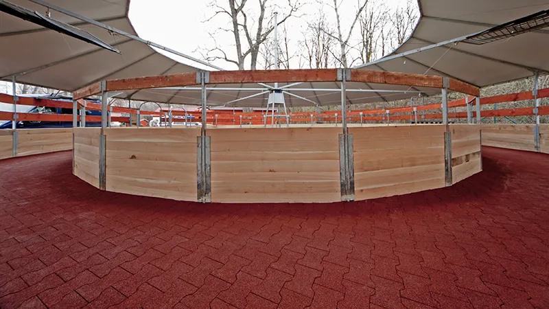 The photo shows a modern, covered horse walker. The track is fully surfaced with red rubber interlocking tiles – slip-resistant, permeable and joint-friendly. The elastic surface enables safe movement of horses in all weather conditions and gaits, reducing strain on hooves, joints and tendons. The paved track is stable, durable and requires very little maintenance. The facility is ideal for riding centres, breeding stables or equine clinics that value animal-friendly surfaces, low maintenance and long-lasting materials.