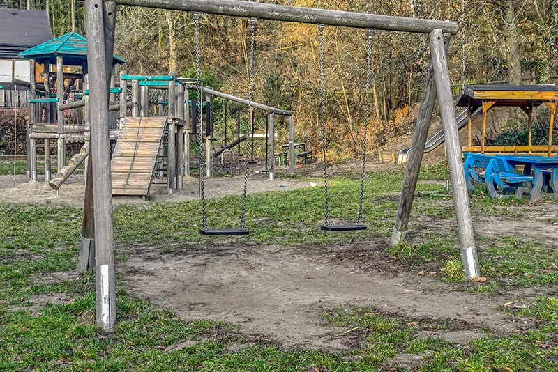 Grass-covered ground is not suitable as fall protection in a playground. The grass is trampled under the swing and the ground is played away.
