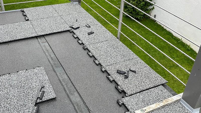 On a balcony, puzzle-shaped tiles made of PU-bonded rubber granulate by WARCO are being installed. Each piece interlocks precisely, creating a nearly seamless, slip-resistant surface. The elastic layer protects the building structure and offers superior walking comfort. Thanks to the simple click-in system, installation is quick and requires no complex preparations, while moisture is effectively drained. Long-term upkeep remains minimal.
